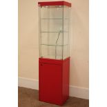 Tall narrow four sided glass shops display cabinet, illuminated interior, cupboard below.