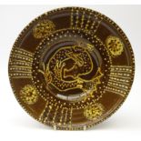 20th century Slipware shallow dish, the central panel decorated with a mythical creature,