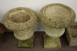 Pair classical style composite stone garden urns on bases,