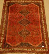 Persian Shiraz red ground rug, triple pole lozenge medallion, decorated all over with animal,