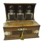 Edwardian oak three bottle tantalus with silver-plated mounts, carved floral panels,