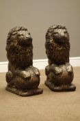 Pair antique bronze finish composite stone seated lions on spherical mounts,