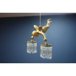 Gilt metal centre light fitting in the form of a cherub, twin branch with cut glass hanging drops,