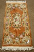 Small Chinese washed woollen rust ground rug with traditional floral pattern,