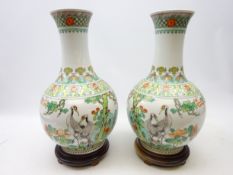 Pair of 20th Century Chinese Famille Verte bottle shaped vases on hardwood stands,