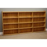 Large early 20th century waxed pine open bookcase, three sections with three tiers, W233cm, H116cm,