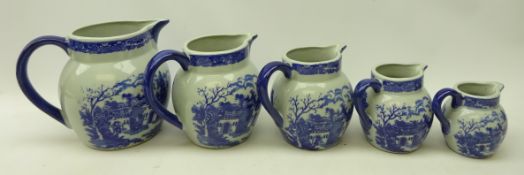 Graduating set of five transfer printed blue and white jugs,