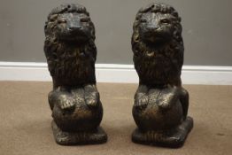 Pair antique bronze finish composite stone garden seated lion figures on spherical mounts,
