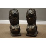 Pair antique bronze finish composite stone garden seated lion figures on spherical mounts,