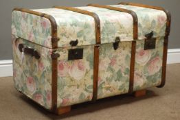 Wooden bound trunk with leather carrying handles, upholstered in floral pattern fabric,