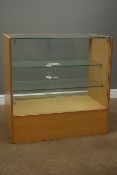 Light wood and glazed shops display cabinet enclosed by sliding glass doors,