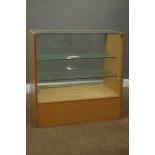 Light wood and glazed shops display cabinet enclosed by sliding glass doors,