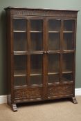 Medium oak bookcase, two glazed and panelled doors with guilloche carved decoration, W107cm, H140cm,