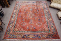 Early 20th century Chinese washed woollen carpet, peach ground decorated with floral motifs,