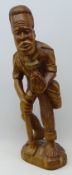 African style carved hard wood figure of a barefoot man holding a pineapple and a hoe,