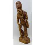 African style carved hard wood figure of a barefoot man holding a pineapple and a hoe,