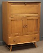 Mid 20th century Ercol elm and beech serving cabinet, fall front enclosing shelf compartments,