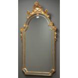 Ornate mirror in gilt cushion frame, shell and floral pediment,