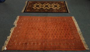 Brick red ground rug with hooked lozenge field, (126cm x 179cm) and hand knotted,