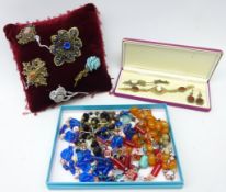 Collection of costume jewellery including brooches mounted on a velvet beaded cushion,