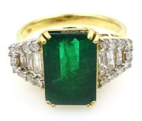 18ct gold emerald ring, with tapered baguette and round brilliant cut diamonds either side,