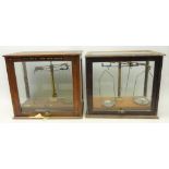 Two chemical balance scales in glazed cases,