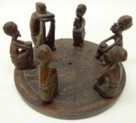 African Native carved hardwood group of six figures seated on circular base,