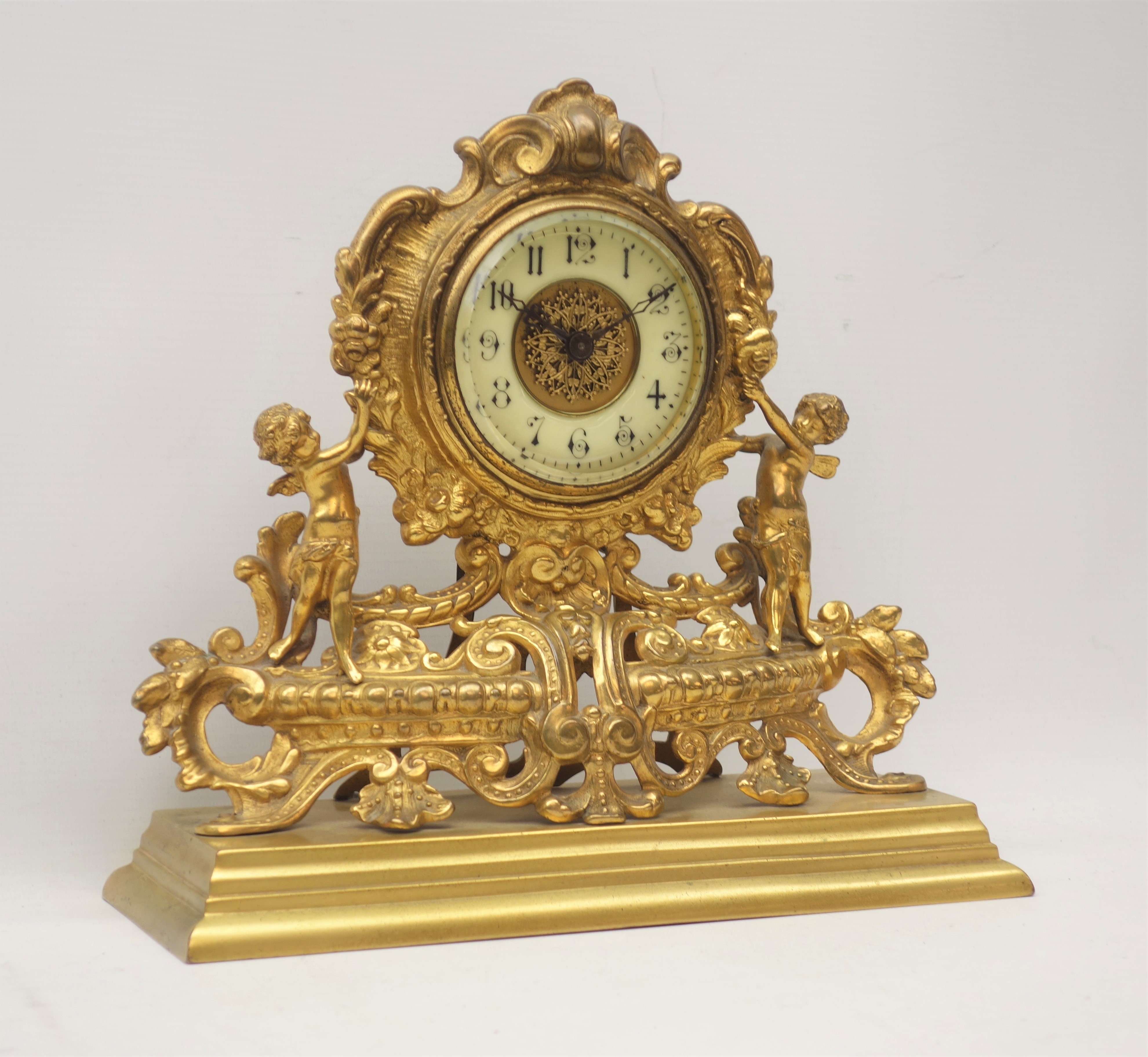 Late 19th century gilt metal mantel clock, ornate cartouche shaped with putto figures,