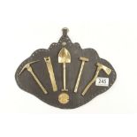 A collection of five miniature brass miners tools displayed on leather mounting G