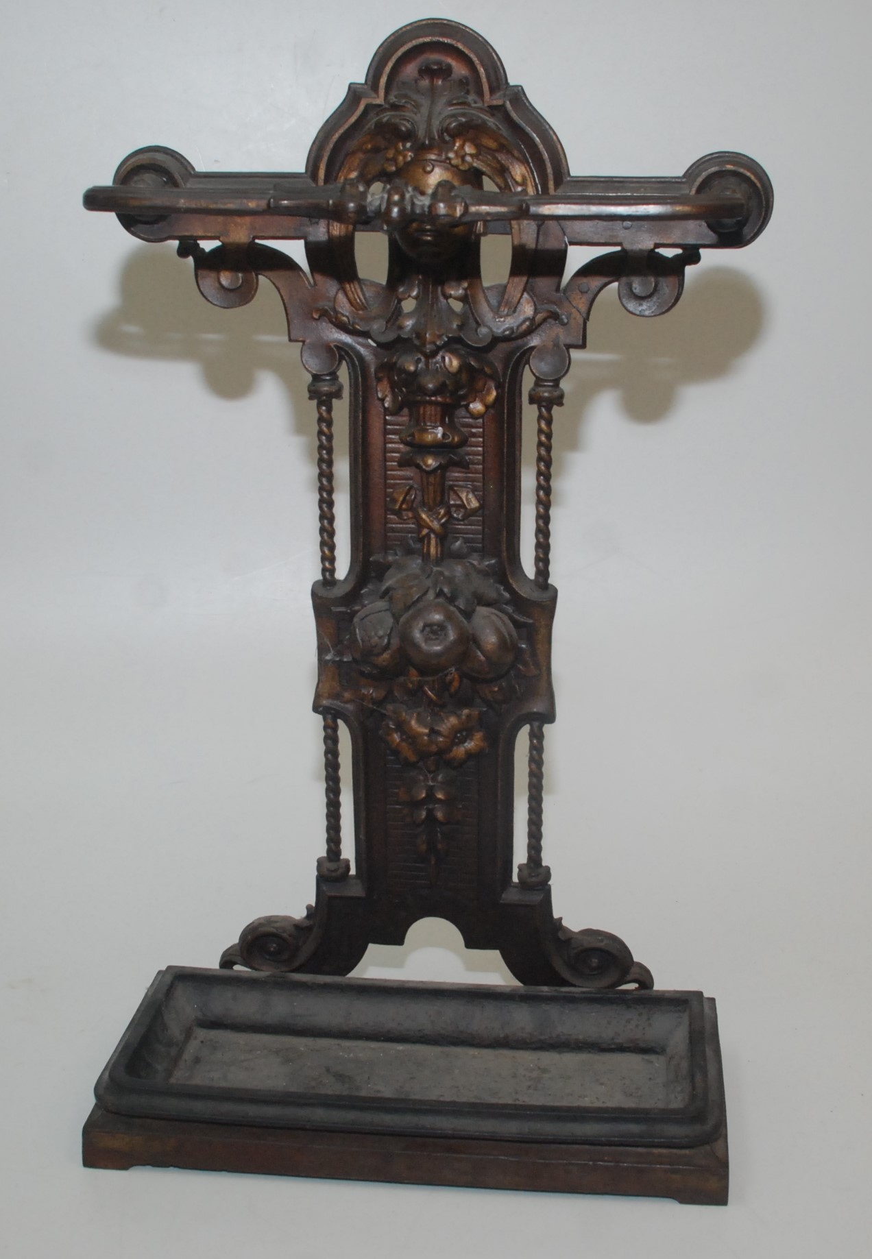 A Victorian iron stick stand cast with the head of a woman above leaves and fruit, height 73cm,