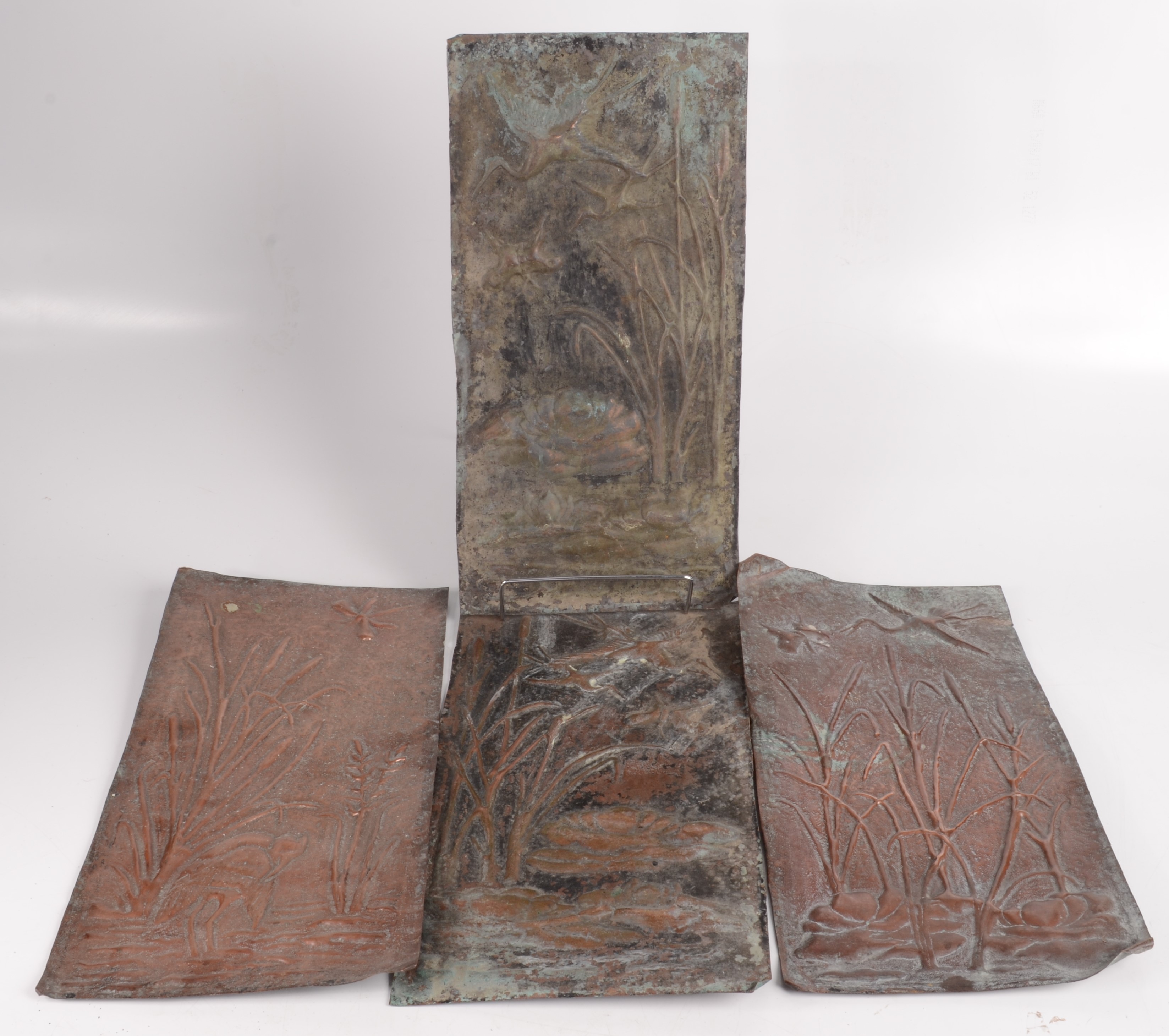 A set of four Arts and Crafts rectangular copper plaques, repousse decorated with reeds,