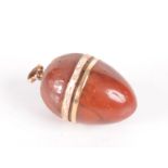 A George III amber and gold egg pendant enamelled in white about its girth on a gold band "gage de