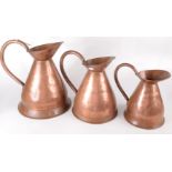 A set of three graduated copper jugs, heights 34.5cm, 29.5cm and 23.5cm.