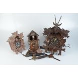 Two Black Forest cuckoo clocks and another wall clock.