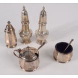 A pair of vase shaped silver pepper pots and a three piece silver cruet with two silver spoons.