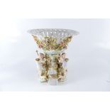 A German porcelain centrepiece, the pierced rose encrusted basket above a rose and putti pedestal,