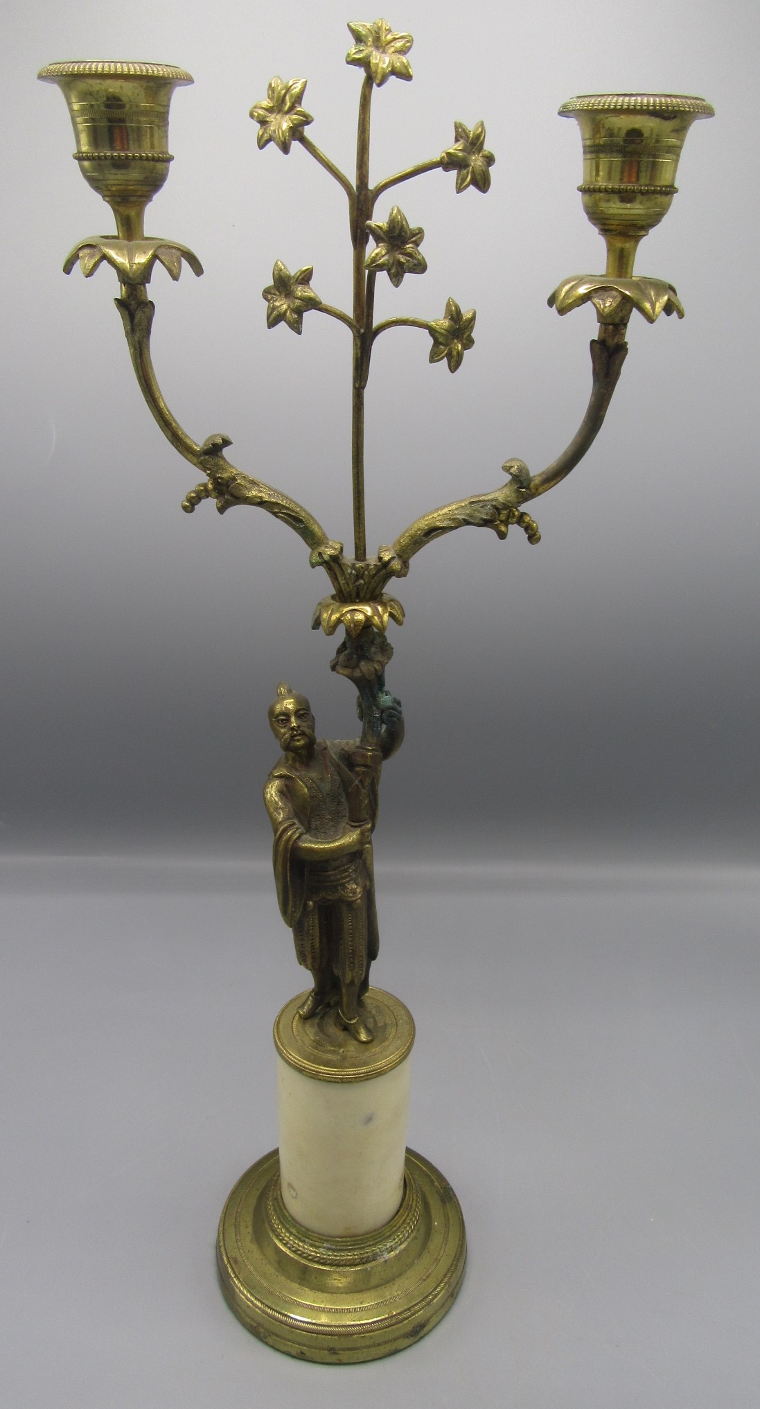 A gilt metal candelabrum, early 20th century, the stem in the form of an oriental gentleman,