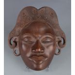 A South East Asian carved wood mask of a female, 27 x 28cm.