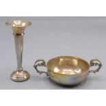 A silver twin handled small bowl and a filled silver spill.