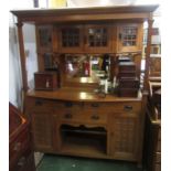 An Arts and Crafts light oak sideboard, the four glazed cupboard doors above three mirrored plates,