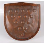 A copper repousse shield showing the fifteen bezants of the Duke of Cornwall, mounted on oak,