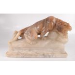 An alabaster lamp in the form of a prowling panther with green glass eyes, on a marble base,