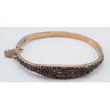 A low purity gold hinged bangle pave set with garnets.