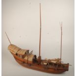 A Chinese wooden model of a junk, with rattan covered roof, length 69cm, width 16cm.