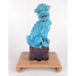 A turquoise porcelain dog of fo, on a purple flambe plinth and wooden stand, total height 27cm,