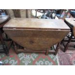 An oak gateleg dining table, on turned and rectangular block supports joined by stretchers,