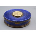 An early 20th century German guilloche enamelled gilt metal oval singing bird music box with a