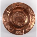 An Arts and Crafts copper charger repousse decorated with stylised dolphins, diameter 61cm.
