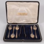 A set of five silver teaspoons with matching tongs.