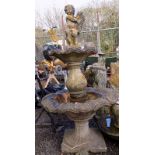 A large composition two tier garden fountain, surmounted by a child holding a stylised fish,